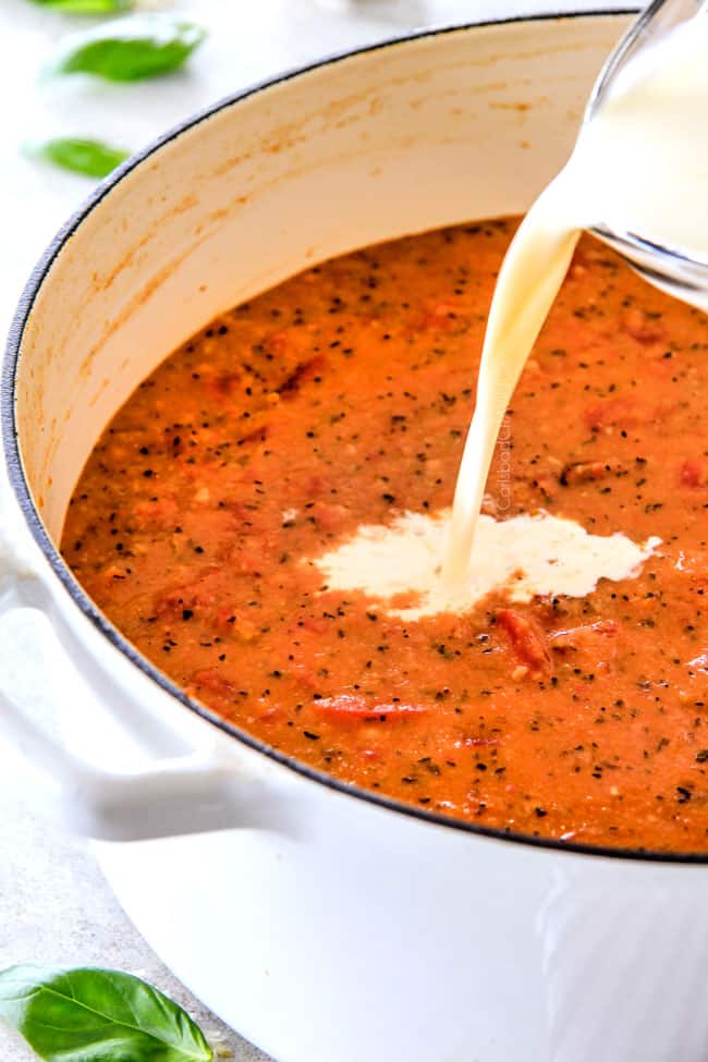 showing how to make tomato basil soup by adding cream to a large pot of tomato soup