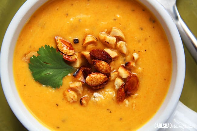 top view of curried butternut squash soup with squash seeds, peanuts and cilantro 