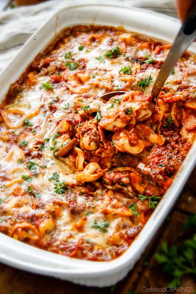 Showing a full pan of Cheesy Tortellini being served with a spoon.