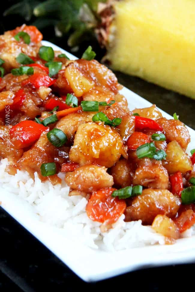 baked sweet and sour chicken over a bed of rice on a white platter 