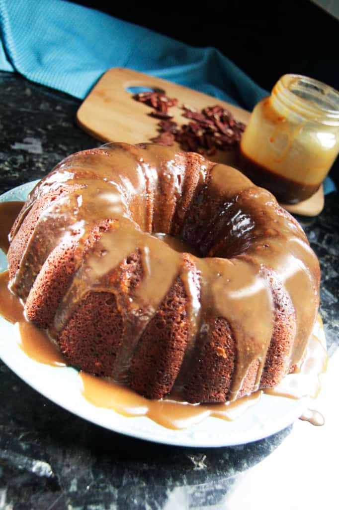 a brown sugar pecan pound cake drizzled with caramel sauce sitting on a white plate