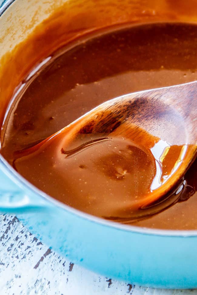 up close of the best caramel sauce stirring with a wooden spoon