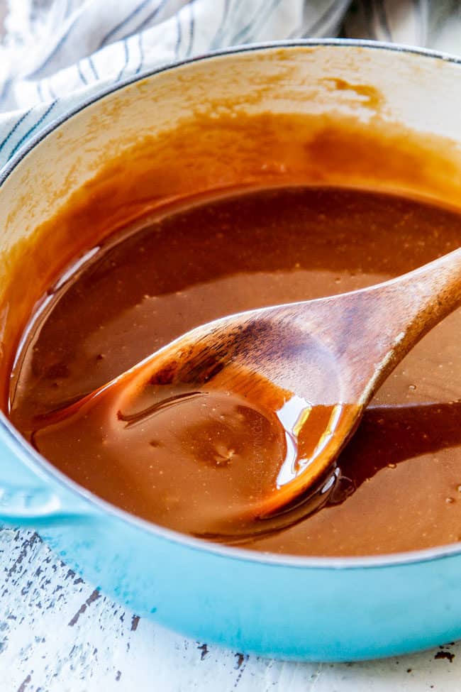 up close of the best caramel sauce stirring with a wooden spoonv