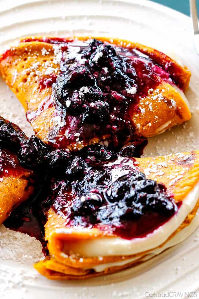 Fresh cooked Carrot Cake Crepes with Cream Cheese Filling and Blueberry Sauce on top.