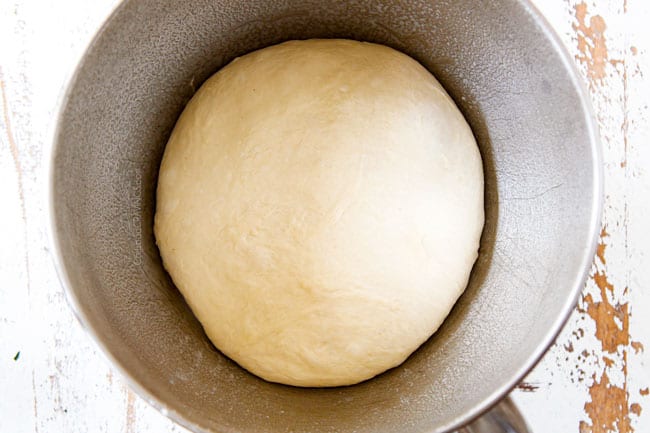 Showing how to make Homemade Pizza Dough by mixing dough in a mixing bowl and letting it rest.