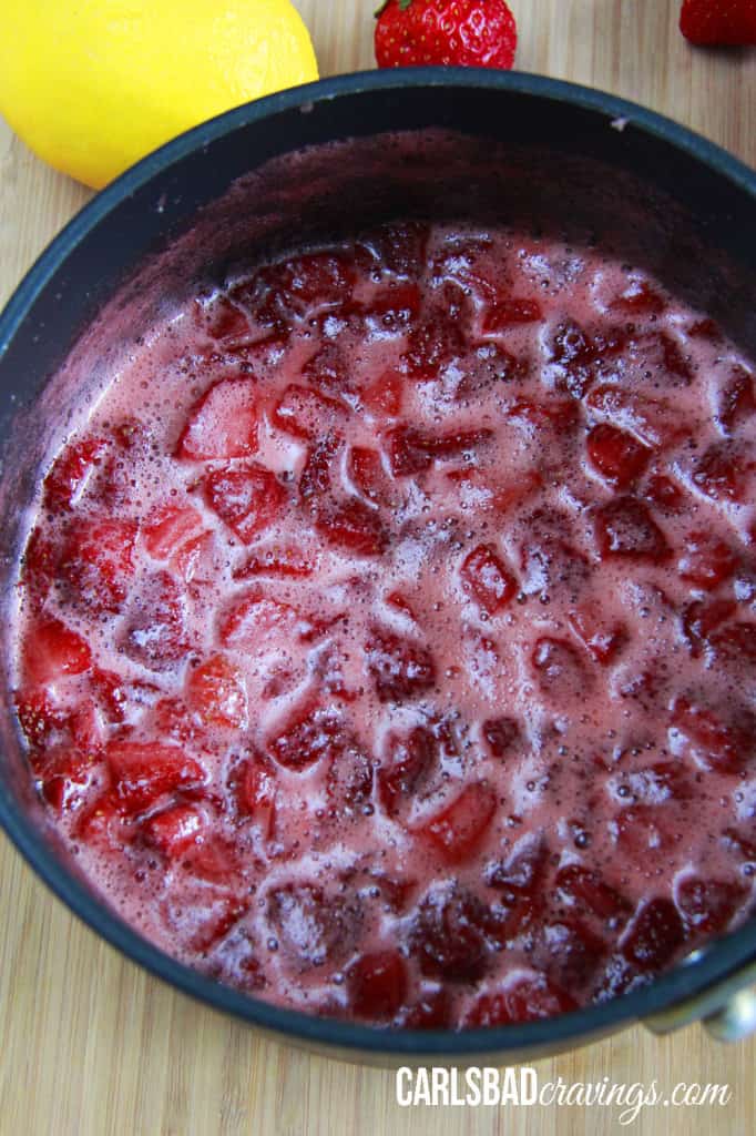 Home made Strawberry Syrup being reduced into syrup in a black pot.