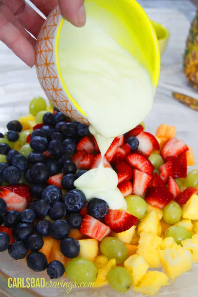 showing how to make fruit salad with yogurt by pouring yogurt over fruit