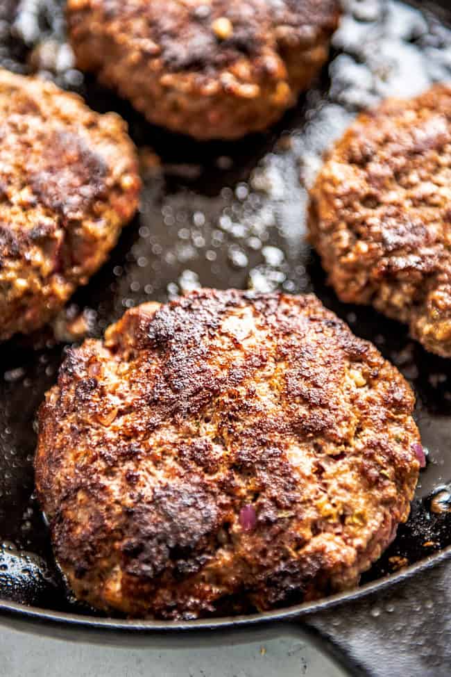 showing how to make the best burger recipe by cooking burgers in a cast iron skillet