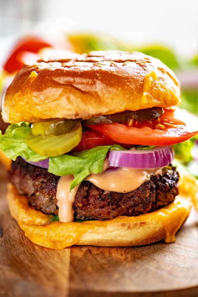 The ultimate burger recipe piled with lettuce, red onions, tomatoes and lettuce