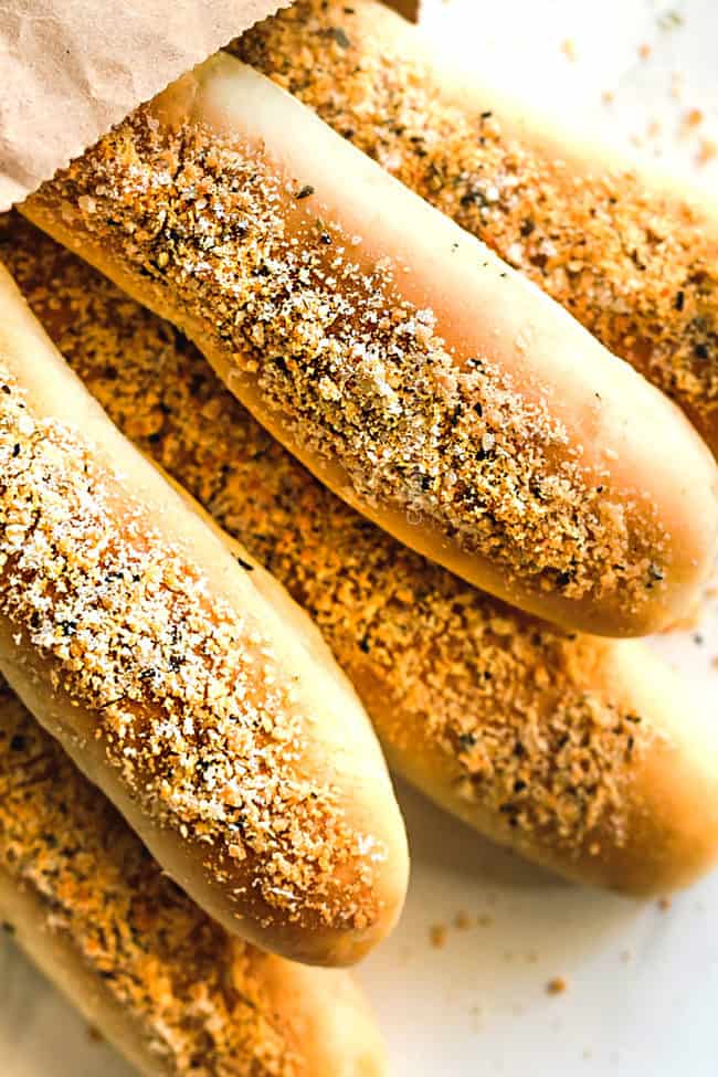 fluffy breadsticks with butter, garlic and Parmesan in a bag laying on a white counter