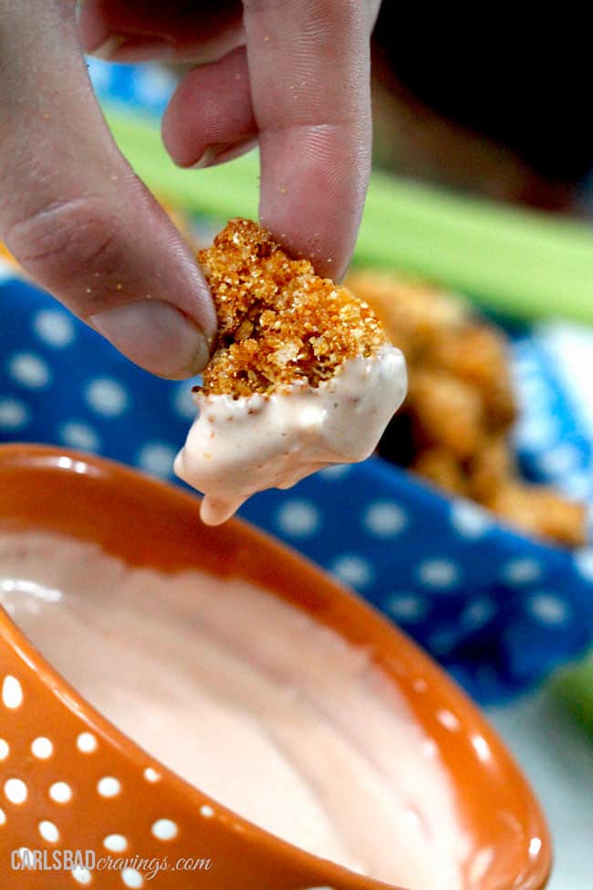 up close of a piece of popcorn chicken in honey buffalo dip