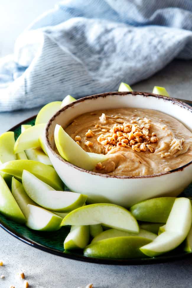 Toffee Apple Dip made with cream cheese, brown sugar, cinnamon in a bowl surrounded by apples