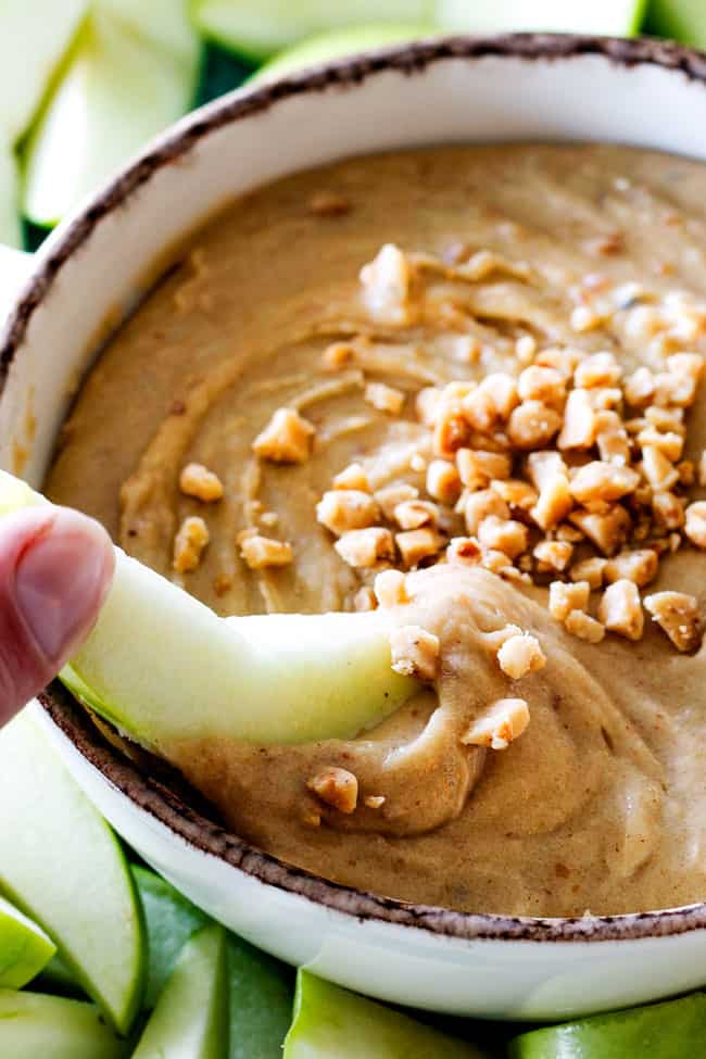 an apple dipping into toffee cream cheese apple dip