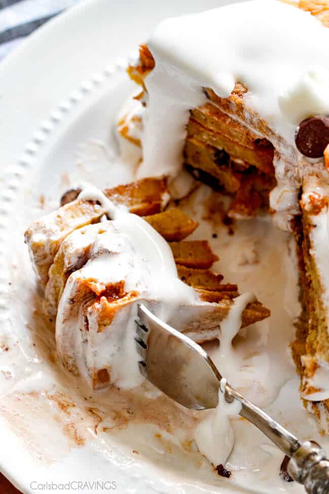 A close up of a fork full of Fluffy S'mores Pancakes pouring marshmallow syrup over top. 