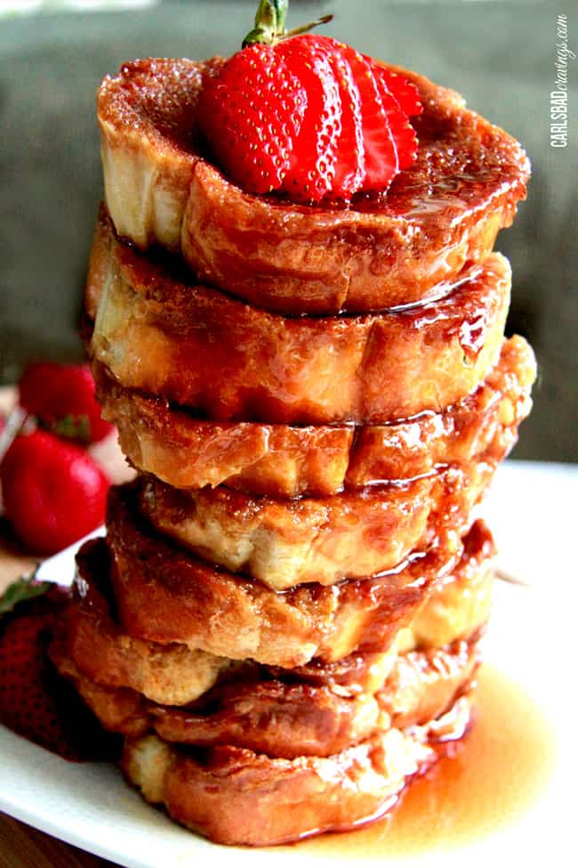 Tall tower of Creme Brulee French Toast syrup and strawberries on top.