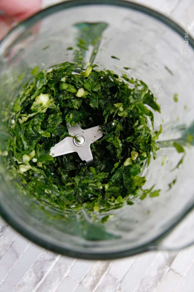 showing how to make chimichurri by  chopping parsley, cilantro and garlic in food processor