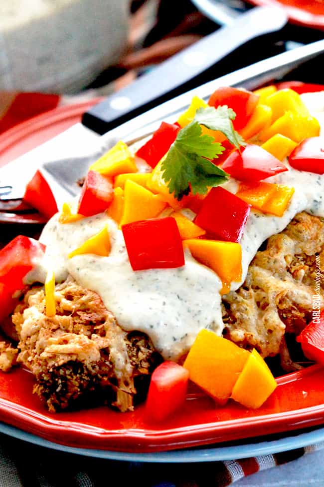 Recipe showing Nacho Chicken with nacho cheese sauce on a red plate and tomatoes.. 
