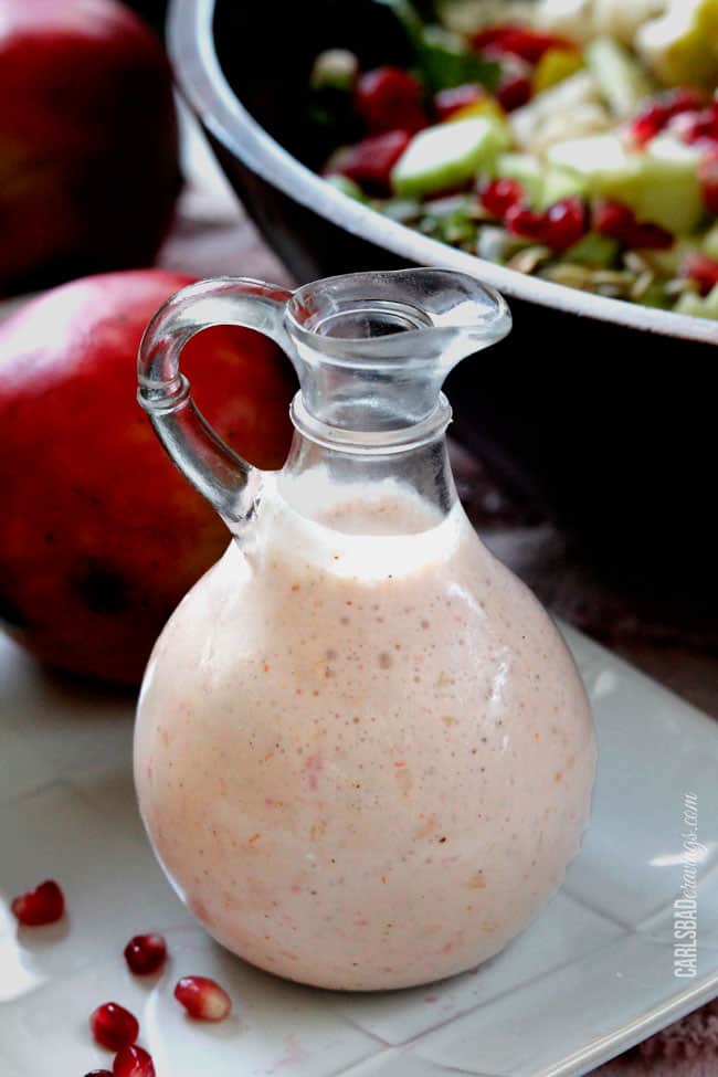 a glass container of pomegranate salad dressing 
