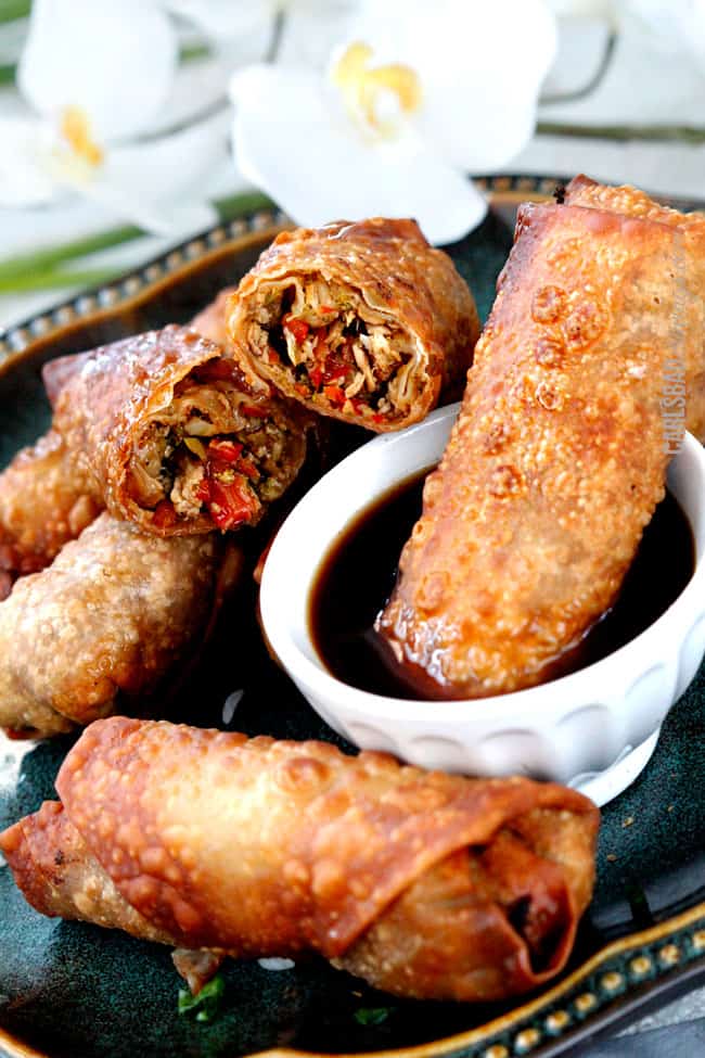 a fried chicken egg roll being dunked in sweet and sour sauce