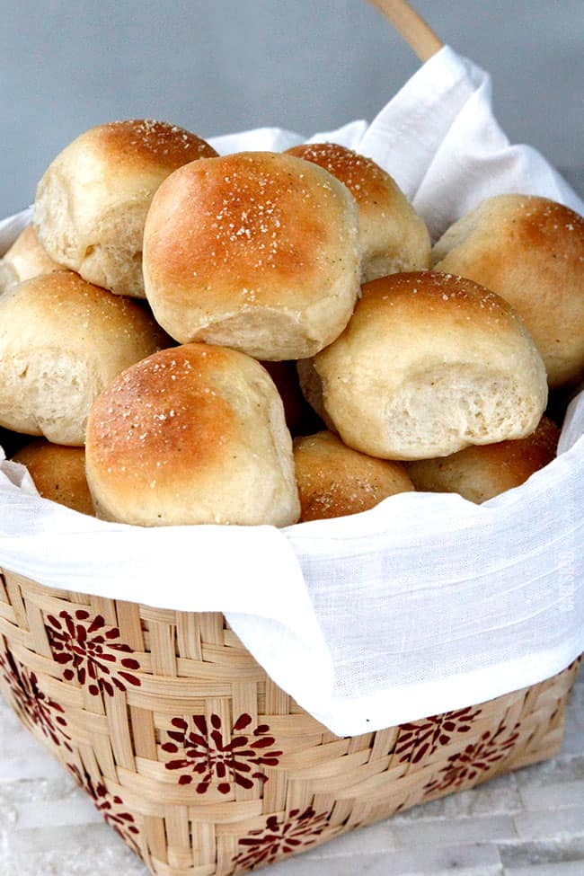 Homemade Dinner Rolls in a woven basket lined with white linen.