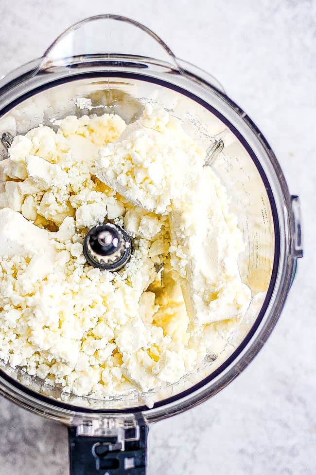 showing how to make whipped feta dip by adding cream cheese and feta to food processor