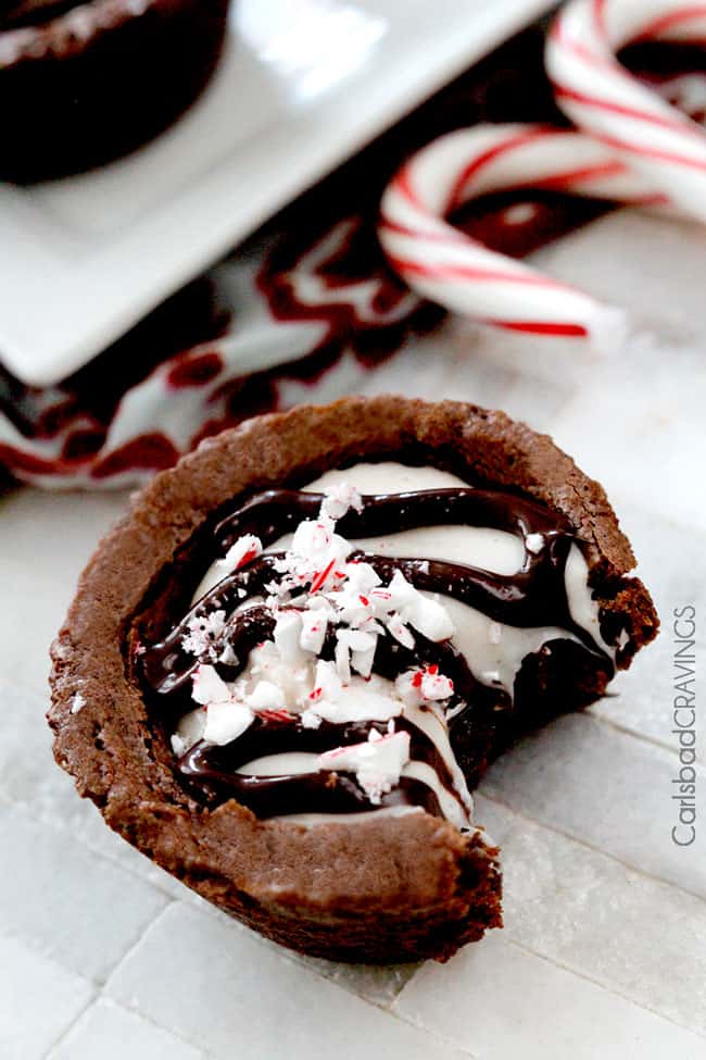 Peppermint Eggnog Brownie Cups with a bite out of it next to candy canes.