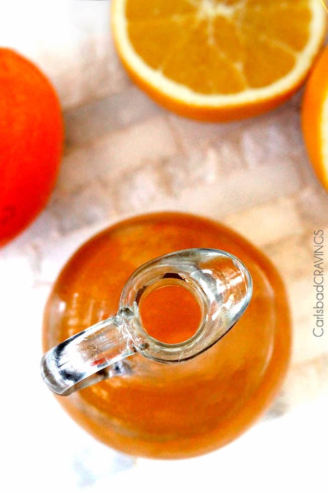 Top view of Orange Syrup in a clear jar next to fresh cut oranges. 