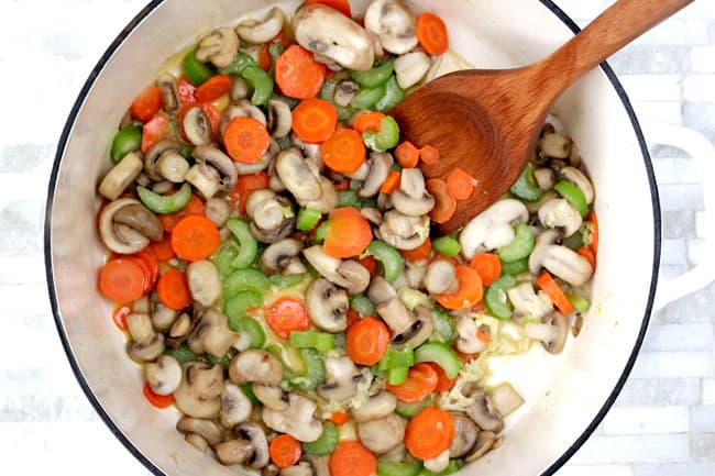 showing how to make meatball soup by cooking carrots, celery, onions, mushrooms and garlic in olive oil in a white soup pot