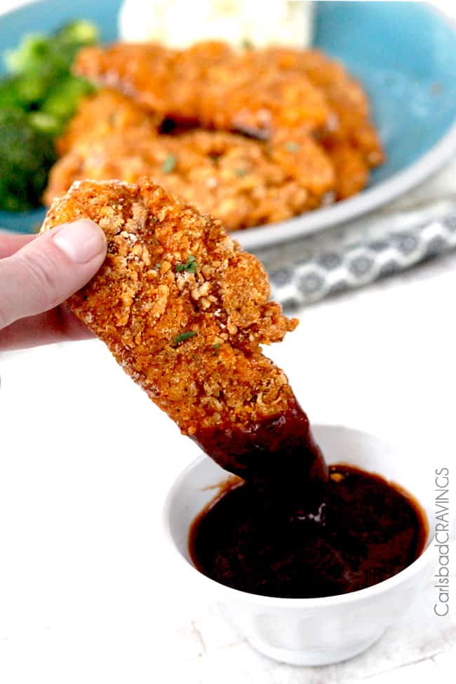 oven fried chicken tender being dunked in bbq sauce