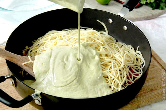 showing how to make Avocado Pasta by adding creamy avocado pasta sauce to warm pasta 