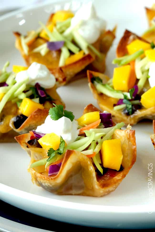 Several baked Tuna Melt Cups garnished with mango, and herbs.