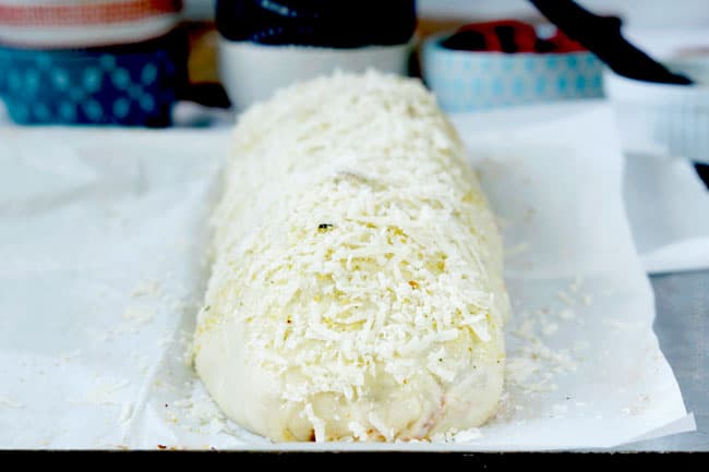 showing how to make stromboli by topping with more mozzarella cheese 