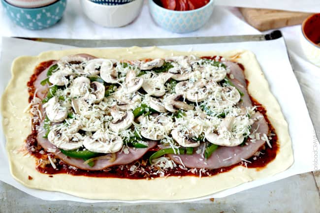 showing how to make stromboli by layering ham with mushrooms, bell peppers and more mozzarella 