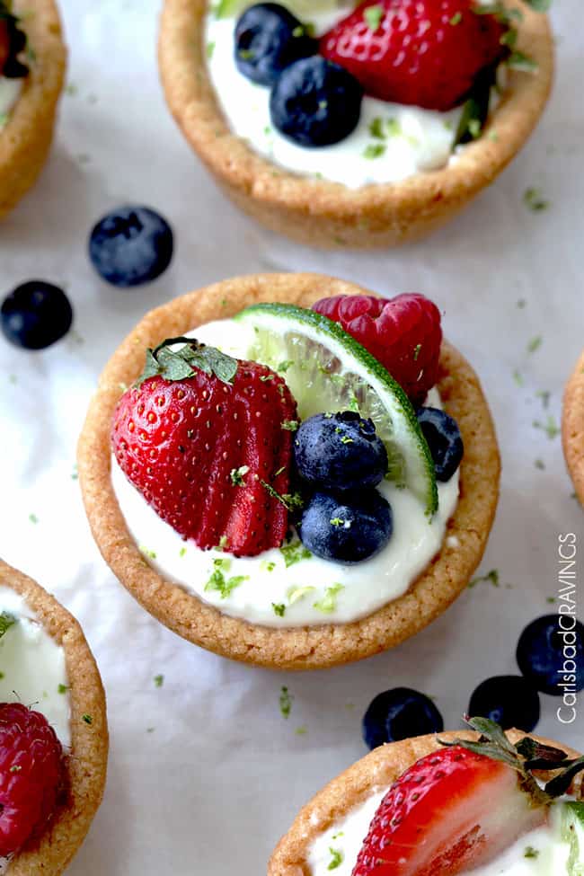 Top view of Key Lime Cheesecake Sugar Cookie Cups with a variety of fruit on top with lime garnish. 