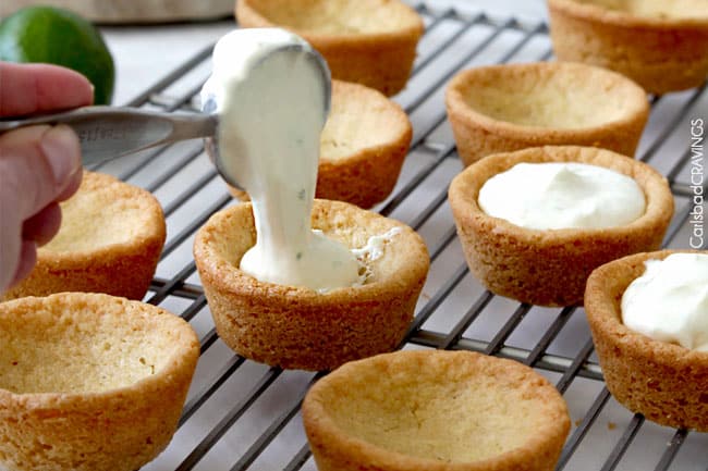 Key Lime Cheesecake Sugar Cookie Cups adding filling to cups.
