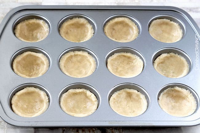 Showing how to make Key Lime Cheesecake Sugar Cookie Cups adding dough to tin. 