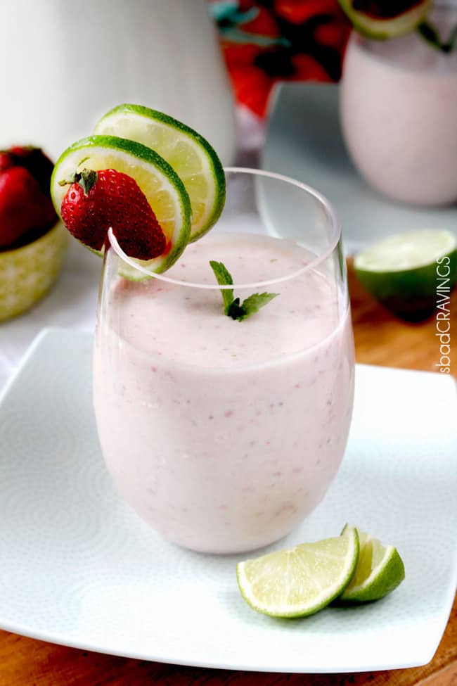 a strawberry banana protein powder smoothie in a glass on a white plate 