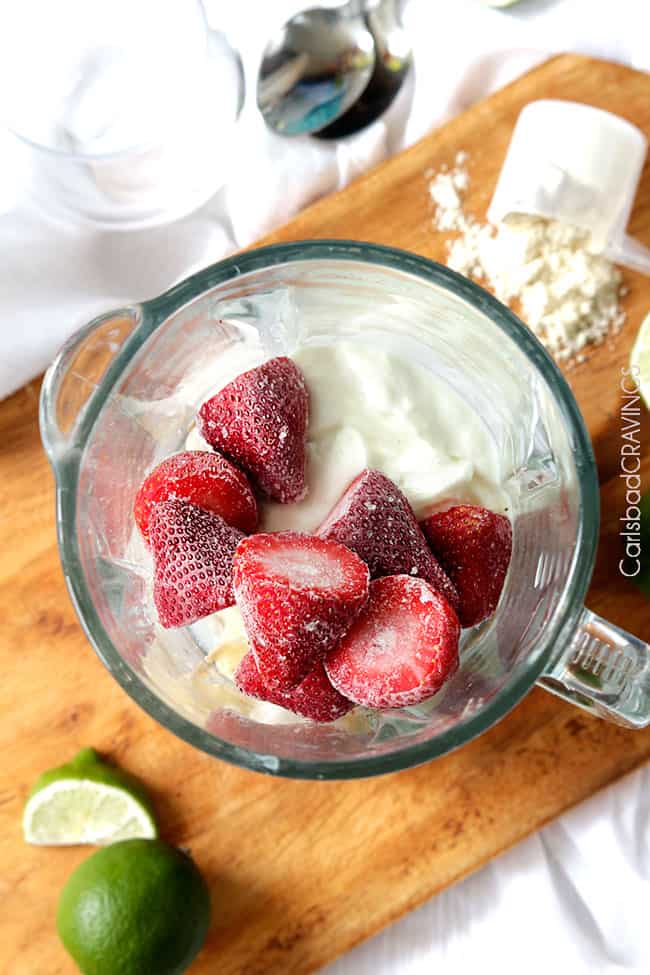 overhead view of a blender full of healthy strawberry banana smoothie ingredients 