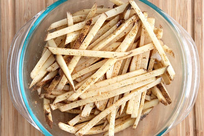 Showing how to spice Baked Mexican French Fries with seasoning on top.