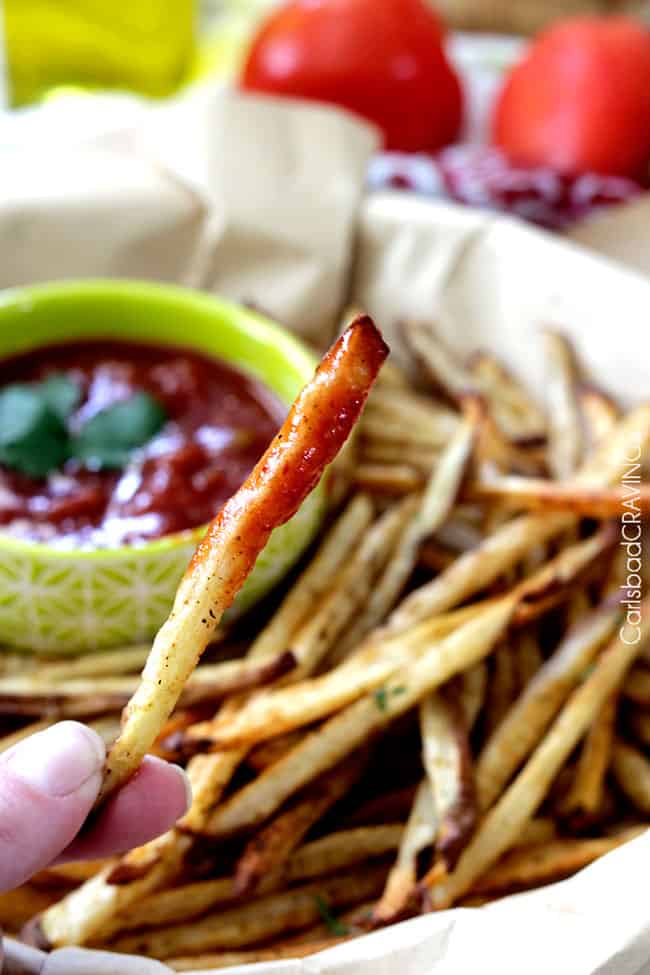 Close up of Baked Mexican French Fries dipped in salsa ketchup. 