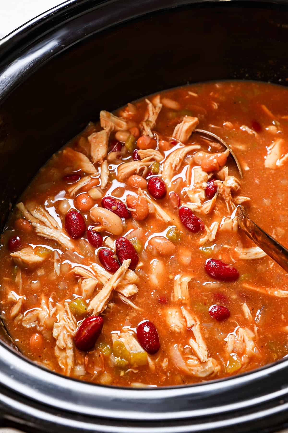 showing how to make chicken chili by stirring it in a crockpot