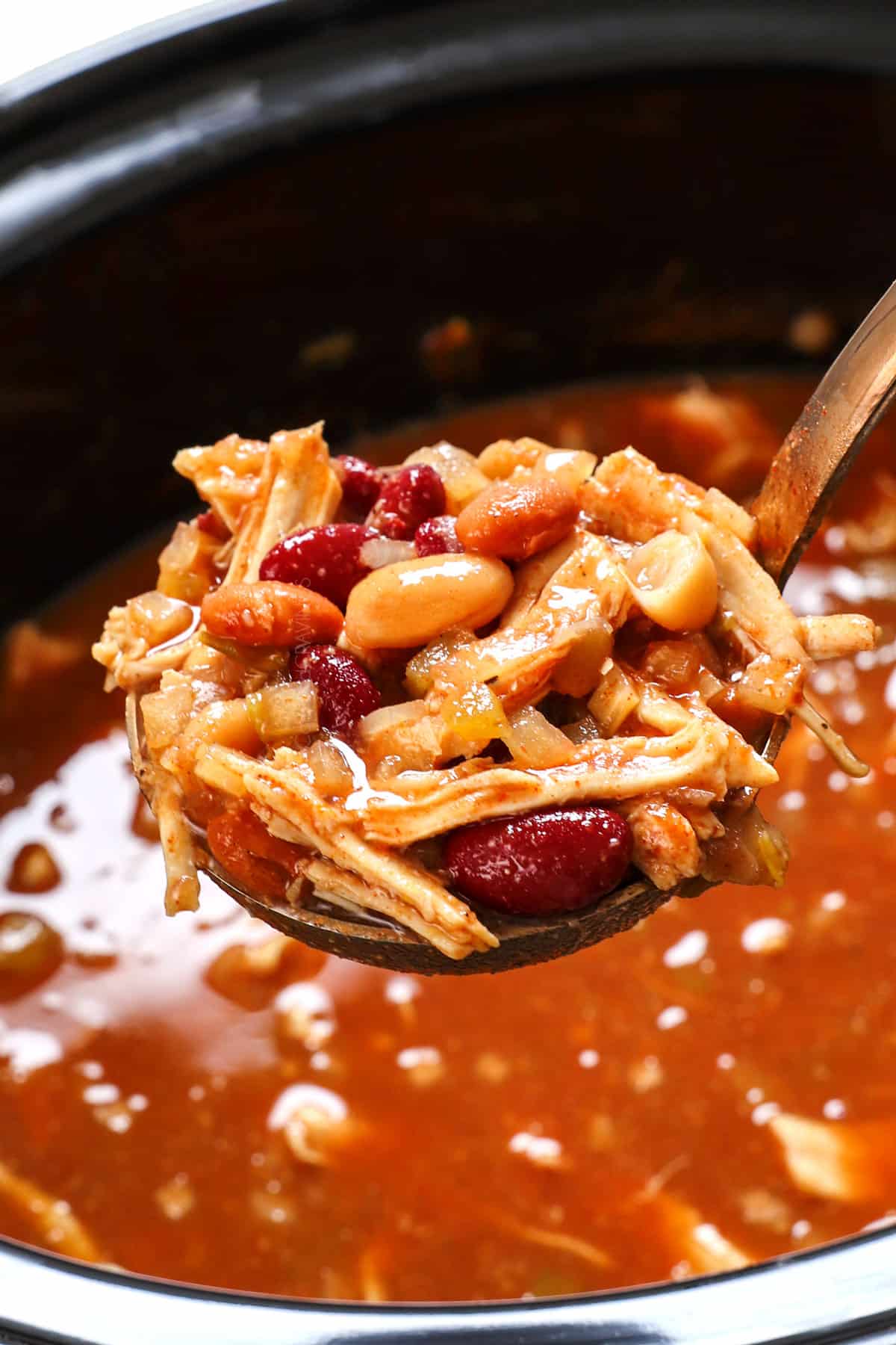 a ladle of crockpot chicken chili showing the thick consistency and ingredients