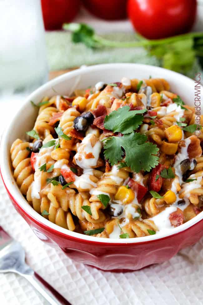 Small red and white bowl of BBQ Ranch Chicken Pasta with green parsley garnish. 
