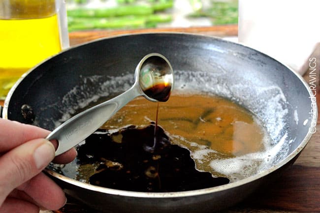 showing how to make balsamic asparagus by adding soy sauce to a skillet of browned butter 