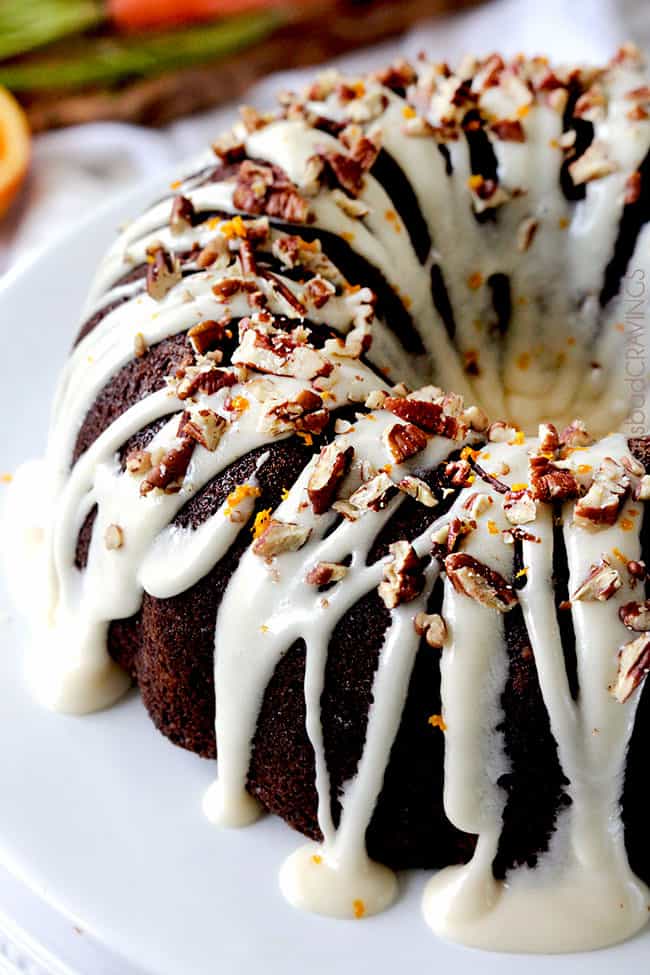 Close up of a full Carrot bundt Cake with Orange Glaze and orange zest with white icing drizzling down.