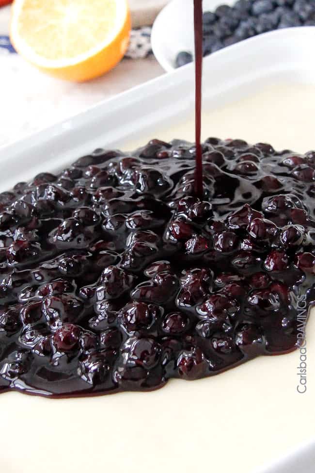 pouring homemade blueberry sauce over cheesecake