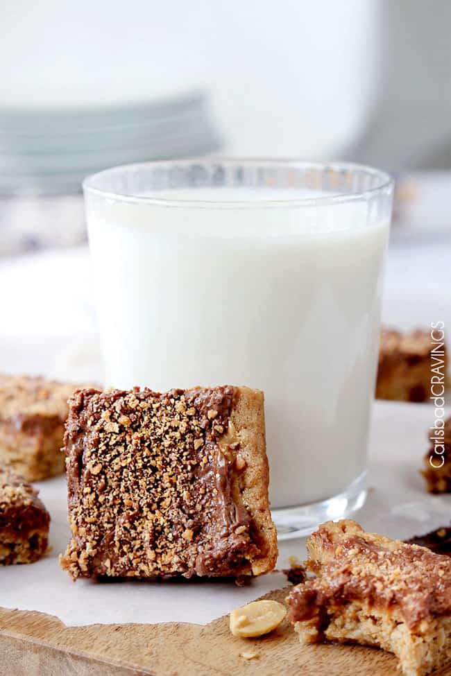 Peanut Butter Cookie Bars leaning up against a cup of milk.