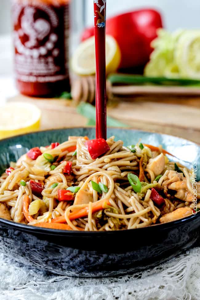 a spicy noodle bowl with a pair of chopsticks sticking out of the top 