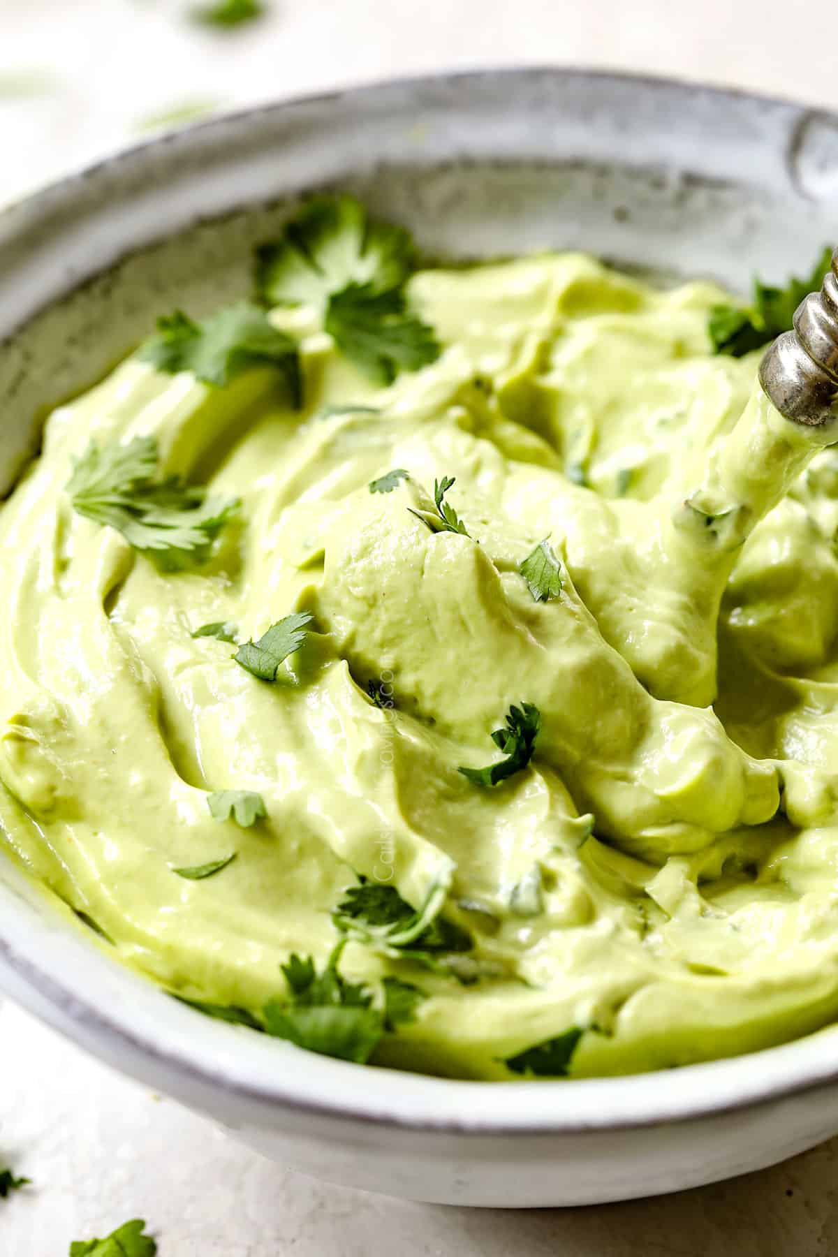 showing how to make pineapple chicken tacos by making avocado crema with avocado, sour cream, mayonnaise and lime juice in a blender