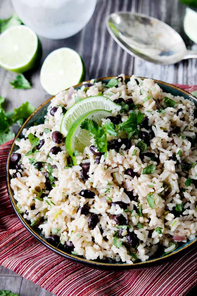 showing  how to garnish Cilantro Lime Rice by sprinkling with cilantro and adding lime wedges to the bowl